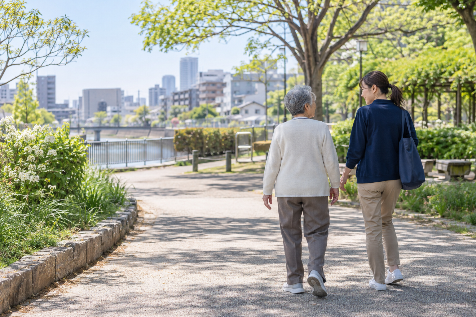 緑のある街なかを並んで歩く高齢者と支援者